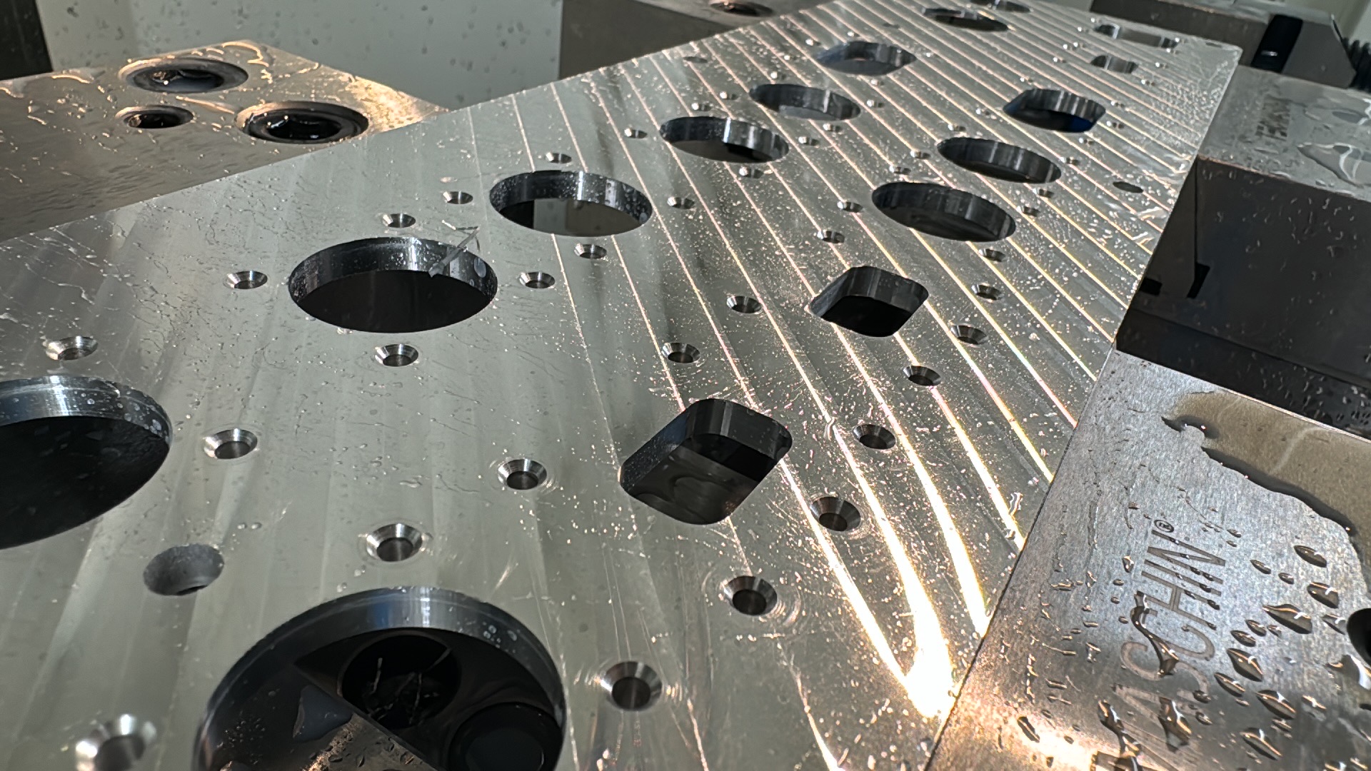 Aluminiumsemne med runde og firkantede udskæringer samt mindre huller i CNC-fræseren.
