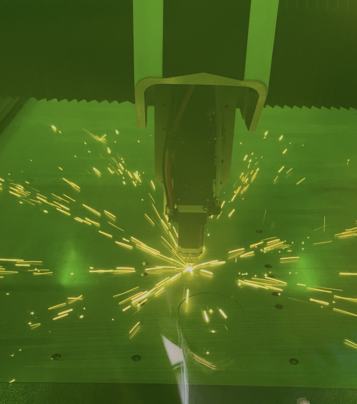 Laserskærehovedet hos KLOI FD skærer en metalplade med gnister omkring skærestedet.